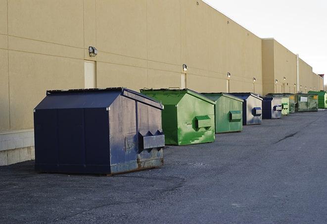 a series of colorful, utilitarian dumpsters deployed in a construction site in Elmhurst